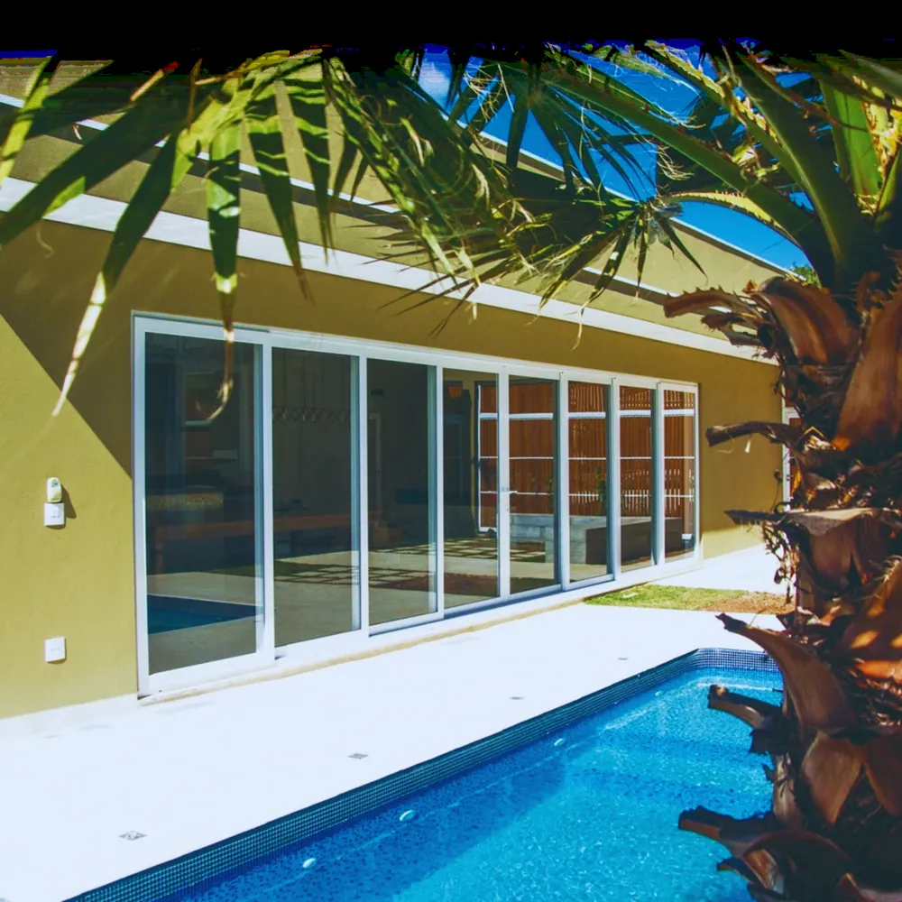 Casa com grandes esquadrias de correr voltadas para a piscina